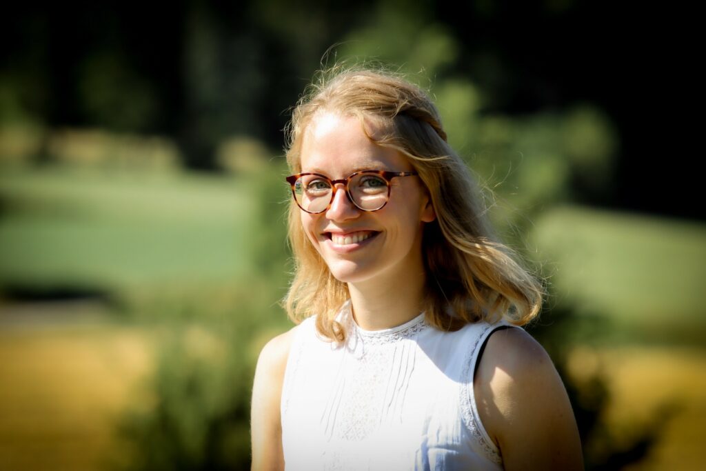 Frau mit blonden Haaren und Brille.